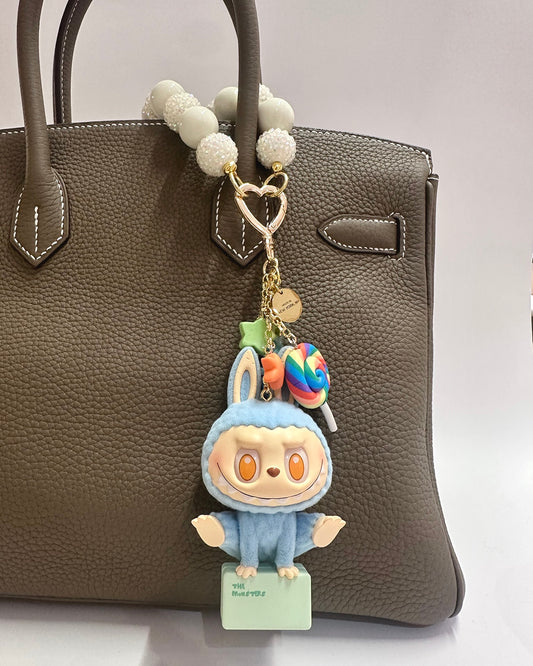 Cartoon character keychain with a lollipop on a brown handbag