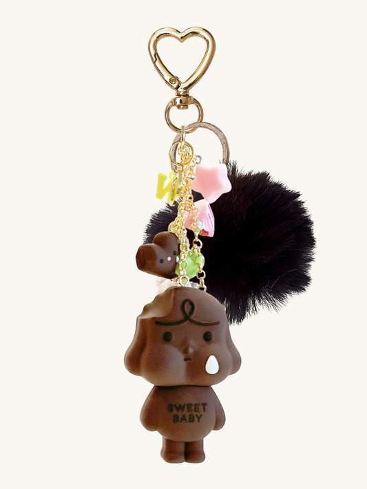 Keychain with a small figure, black hair, and heart-shaped keyring on a white background