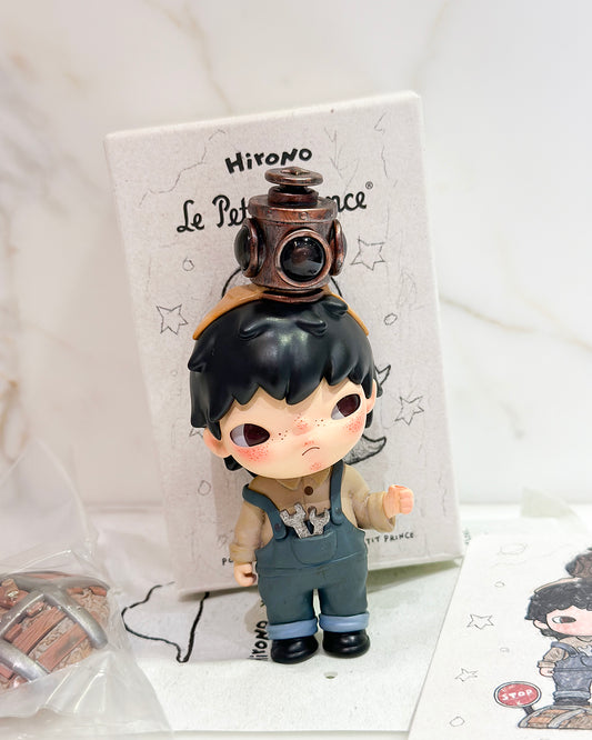 Small figurine with a lantern on its head, standing in front of a branded box.